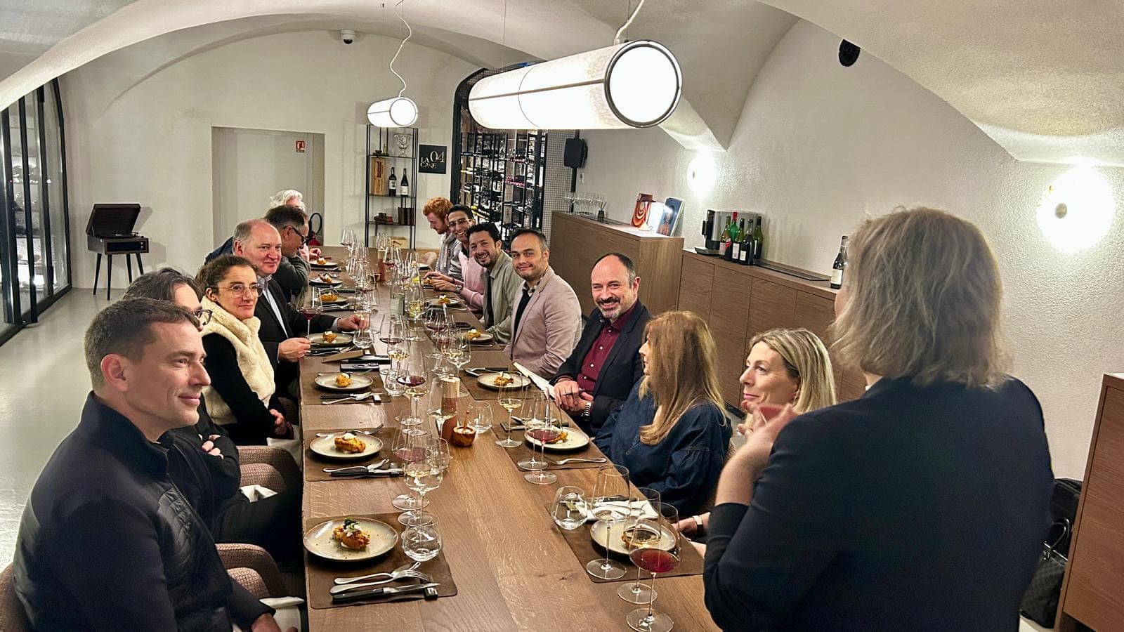 Longue tablée de convives lors d’un wine dinner dans une cave voûtée